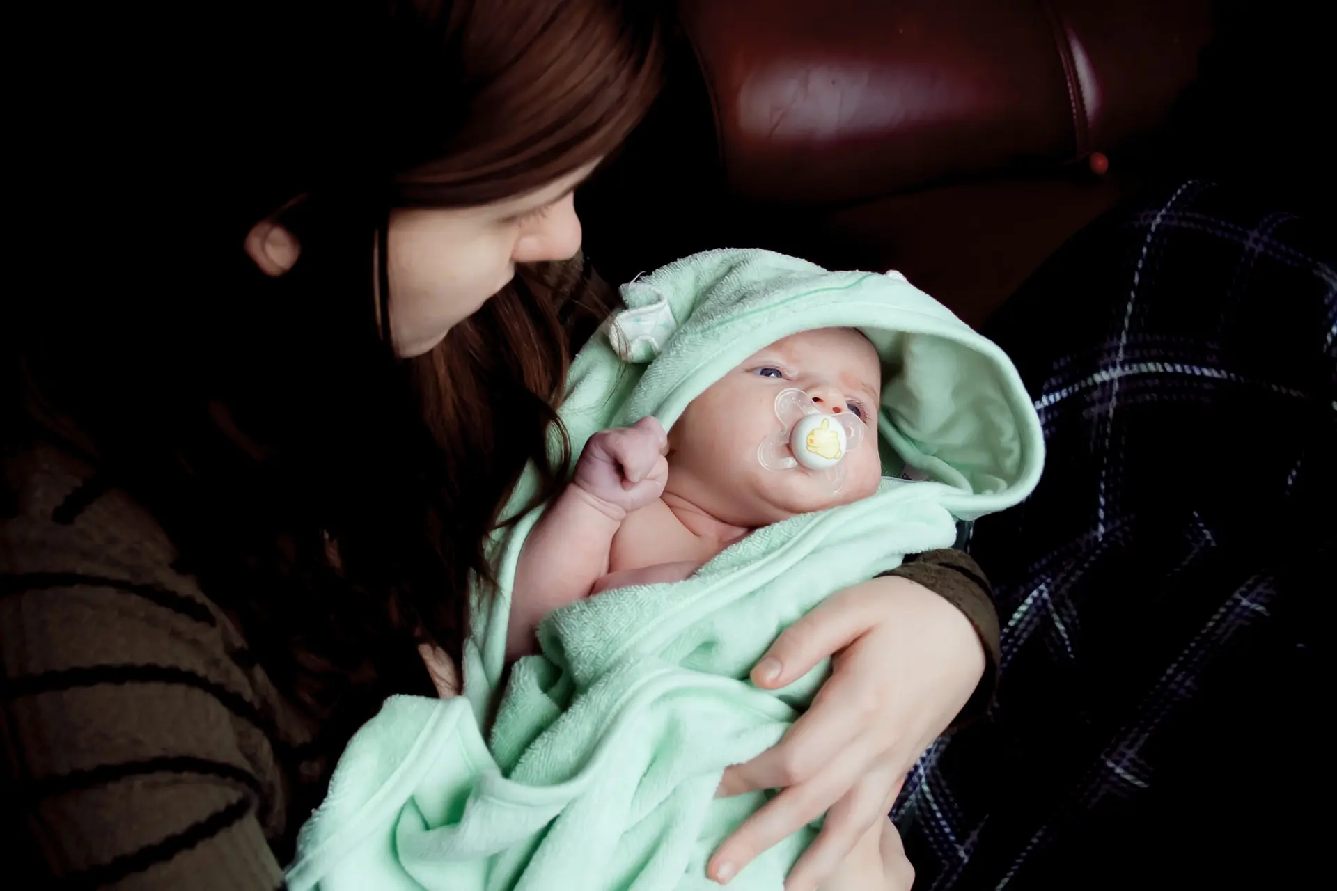 Mother holds her swaddled baby in her arms.