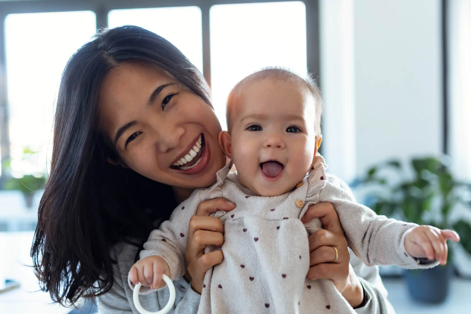 an asian woman and her baby smile for a photograph