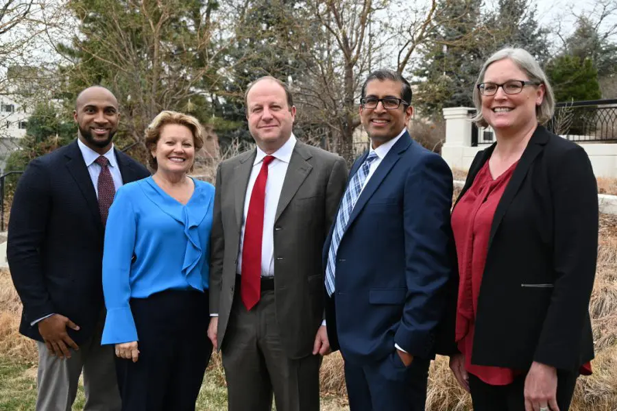 Four people gather for a photo outside with Colorado Governor Jared Polis