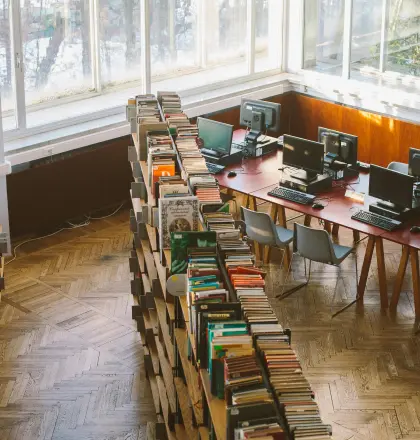 An overhead view of a library with two rows of books and a computer area