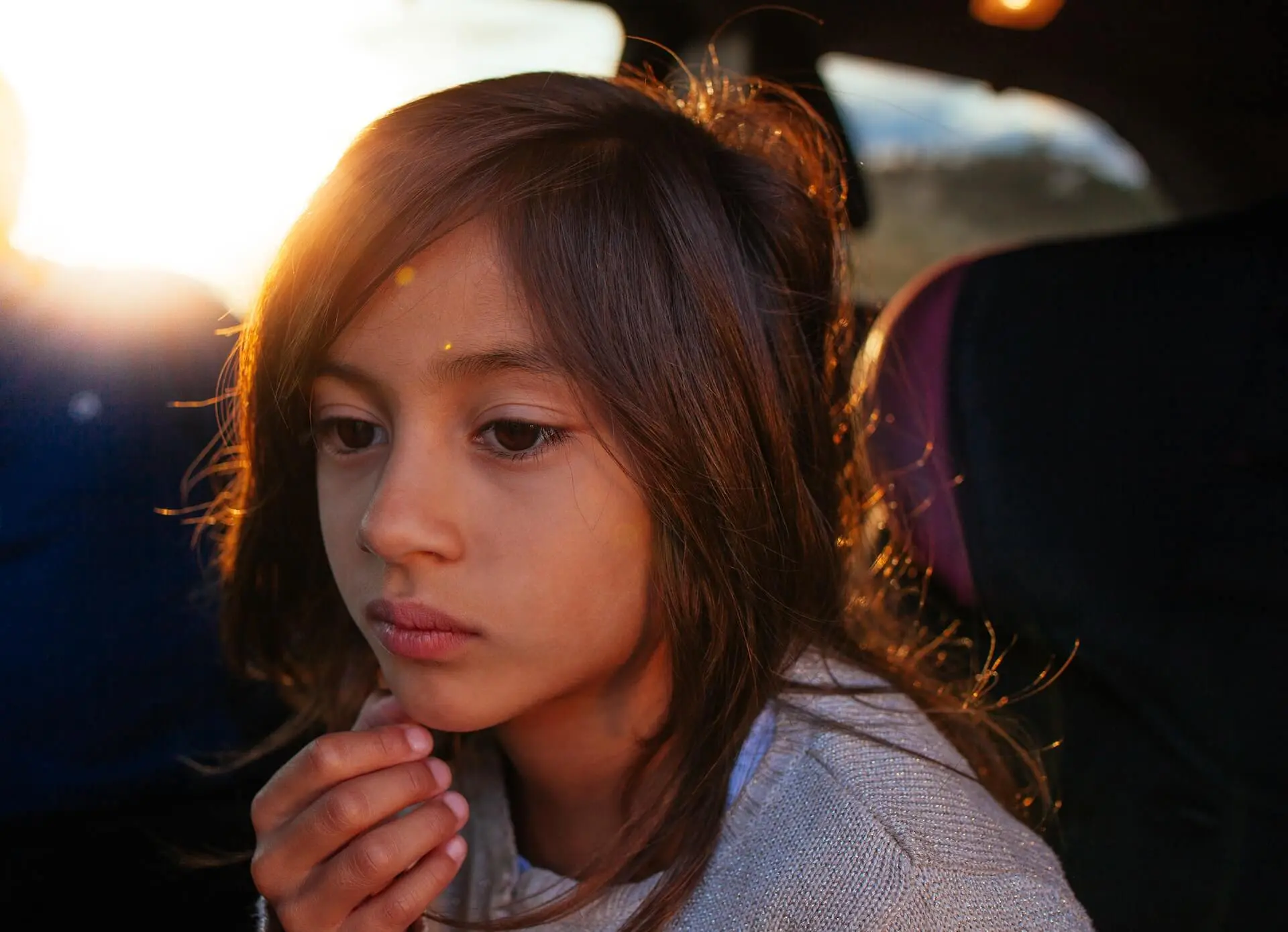 A thinking child sits in a car.
