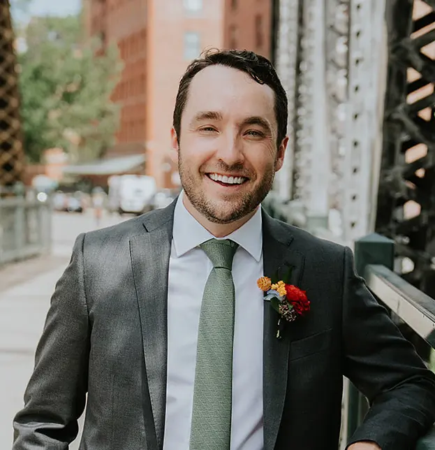 a man in a gray blazer and corsage