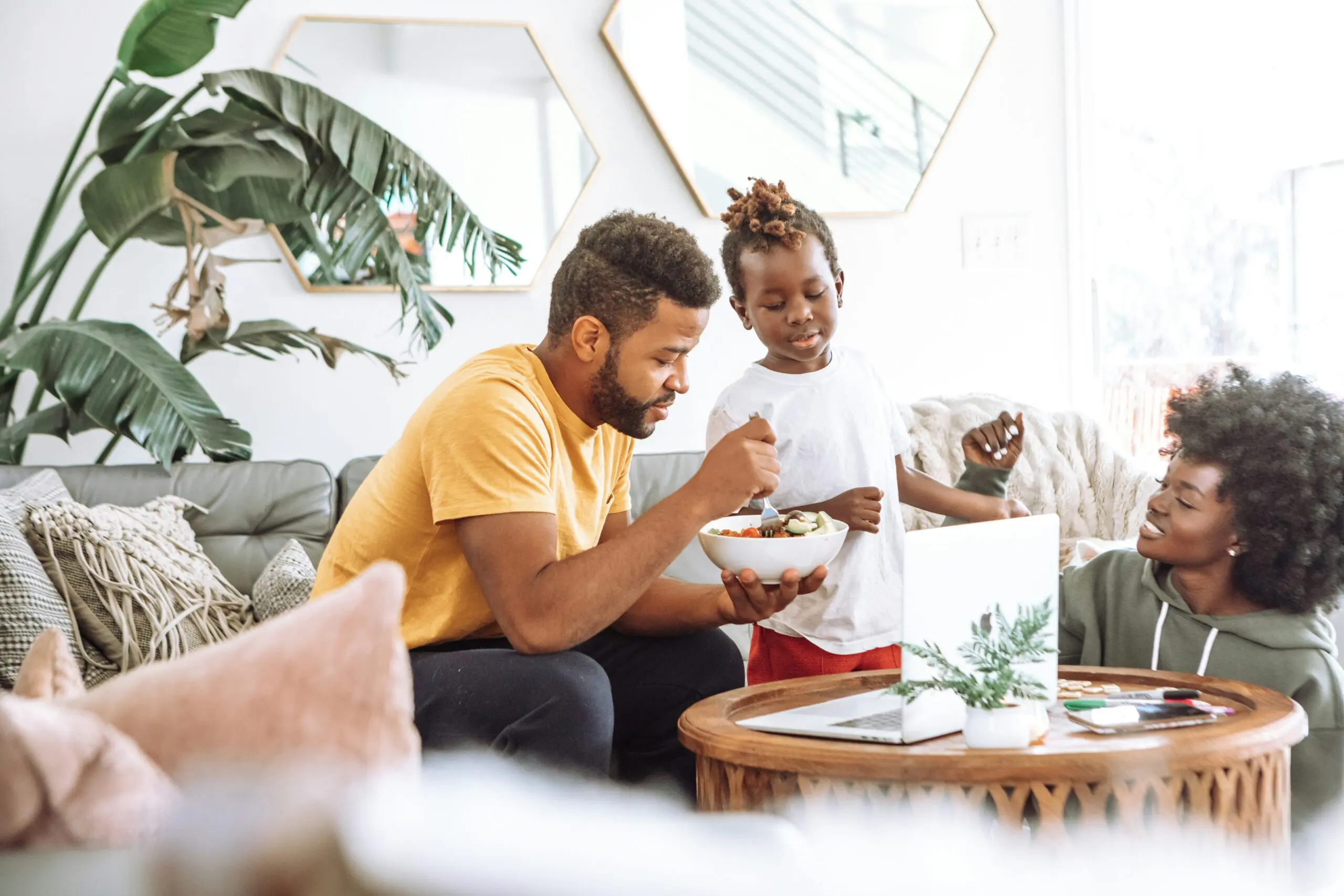 two african american parents share a salad with their young son