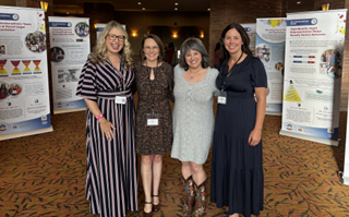 Picture1 - Colorado Evaluation & Action Lab four women stand in front of storyboards at a conference