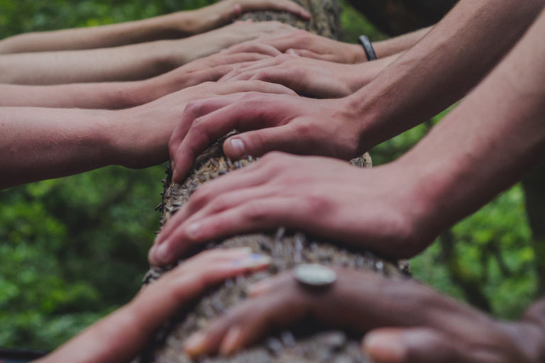 many hands pushing on a log