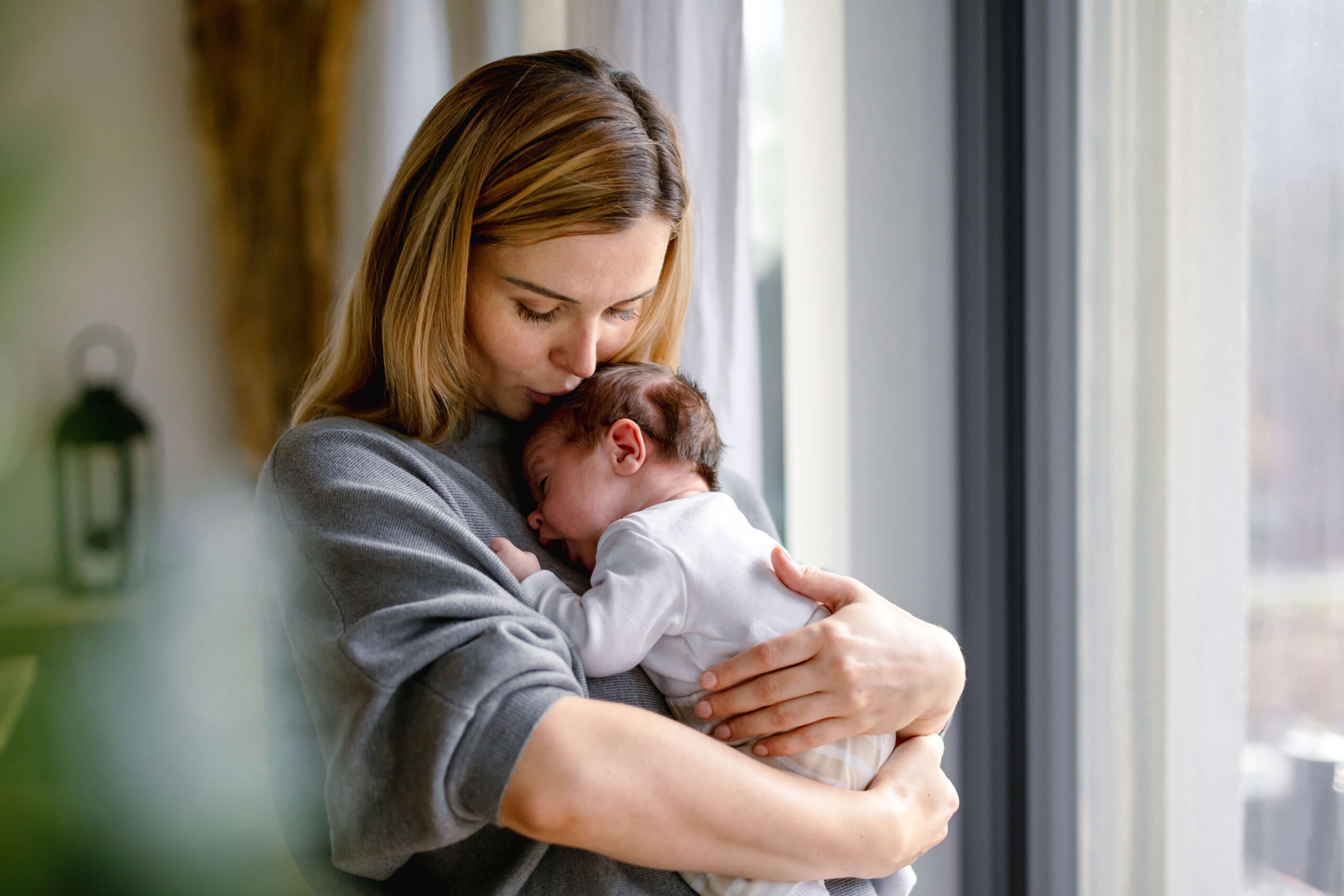 Loving mother hugs her little baby at home